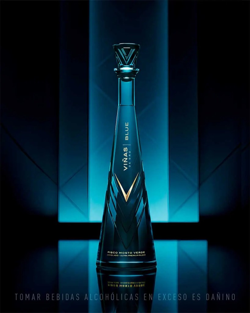 Botella de pisco Viñas Blue sobre un fondo iluminado en tonos azul y negro.