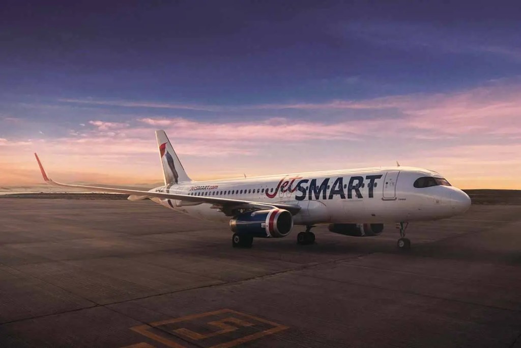Un avión de la aerolínea JetSMART en el aeropuerto durante el atardecer.
